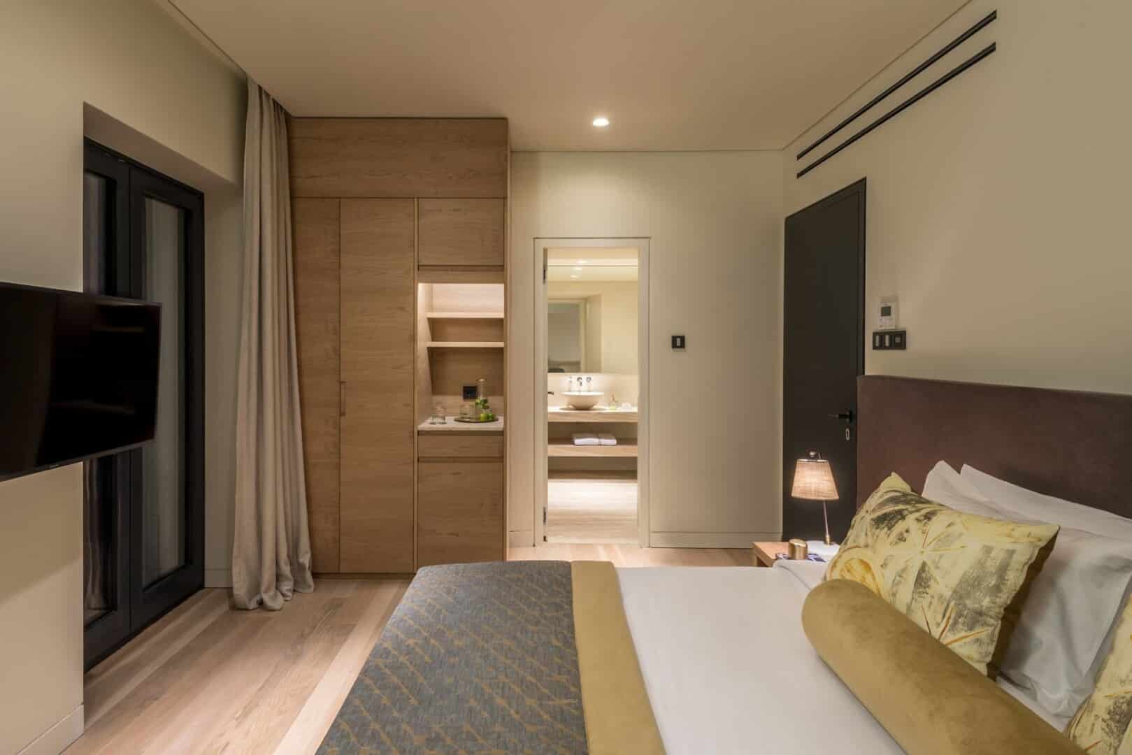 Side view of our Classic Room, showing the bed neatly made the wardrobe with water break area and open door leading to the bathroom.