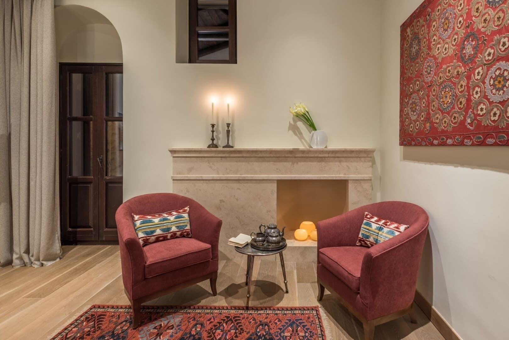 The inviting tea spot at our Superior Deluxe rooms, featuring two red armchairs, red floor carpet and similar design on wall.