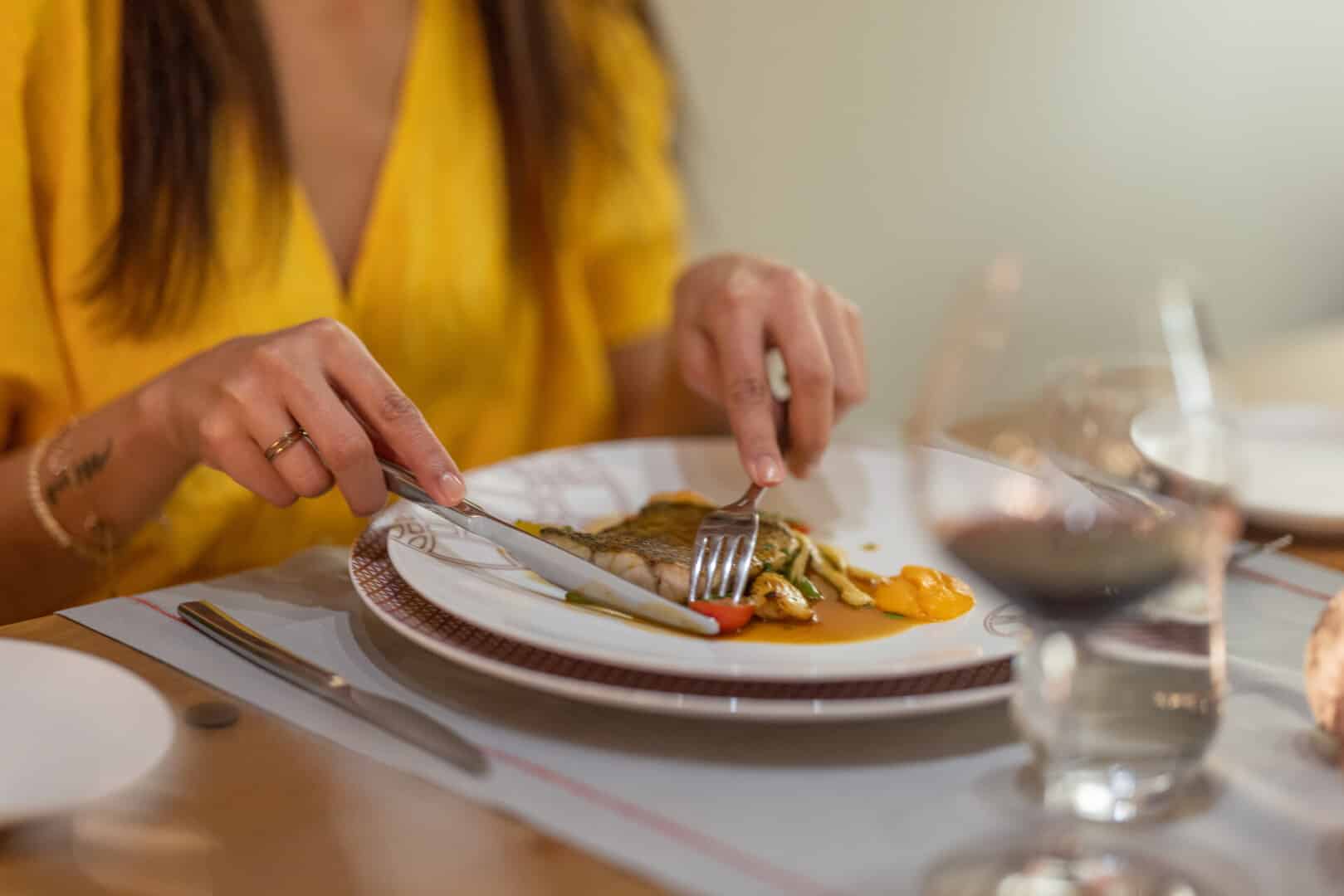 Close-up of a woman guest tucking into a fish fillet dish at Euphoria Retreat.
