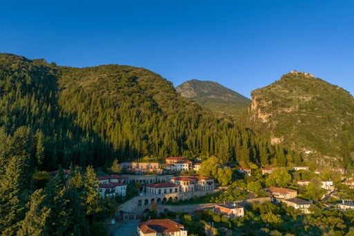 The verdant embrace of Euphoria Retreat, amidst the green forest at the foothills of mount Taygetus and the castle of Mystras in the background.