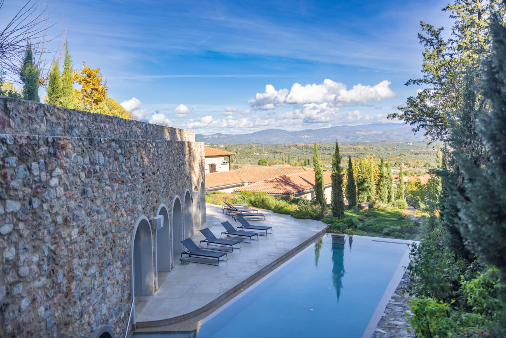 View from over the rectangular pool with sun loungers at Euphoria Retreat, showing the beautiful verdant landscapes sprawled in front of it.