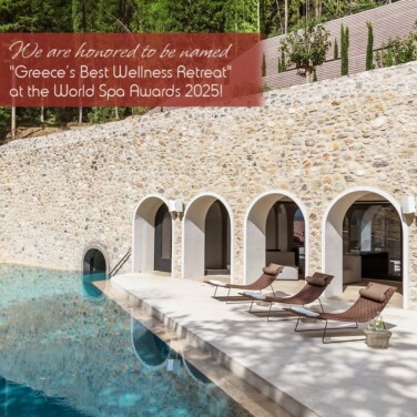 Poolside view at Euphoria Retreat with stone wall arches and lounge chairs, announcing the award of Greece’s Best Wellness Retreat at the World Spa Awards 2025.