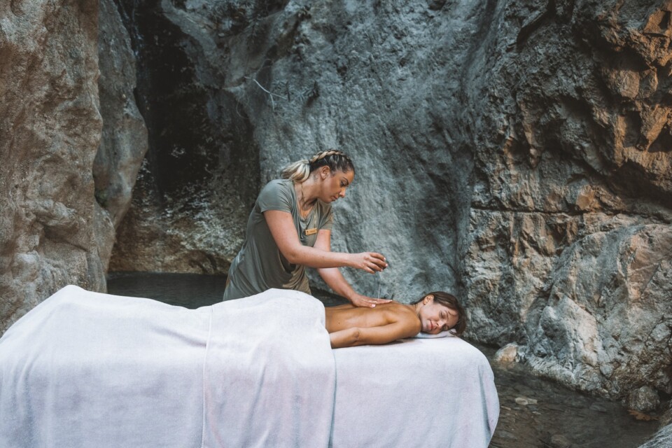 Therapist giving an outdoor massage by a rock pool at Euphoria Retreat, best spa for solos seeking nurturing, transformative wellness